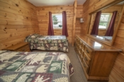 bedroom with wood walls, beds and dresser