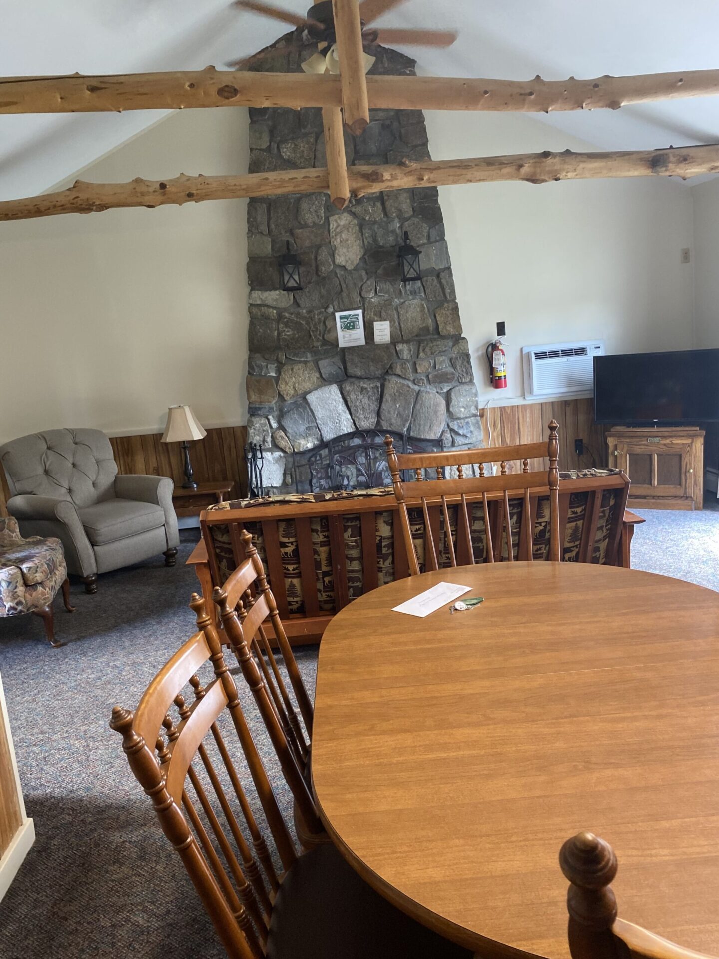 large stone fireplace surrounded by sofa and chairs in living room with dining table