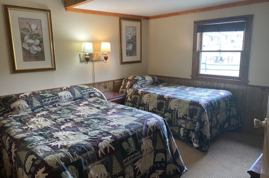 2 beds in bedroom with Adirondack themed blankets