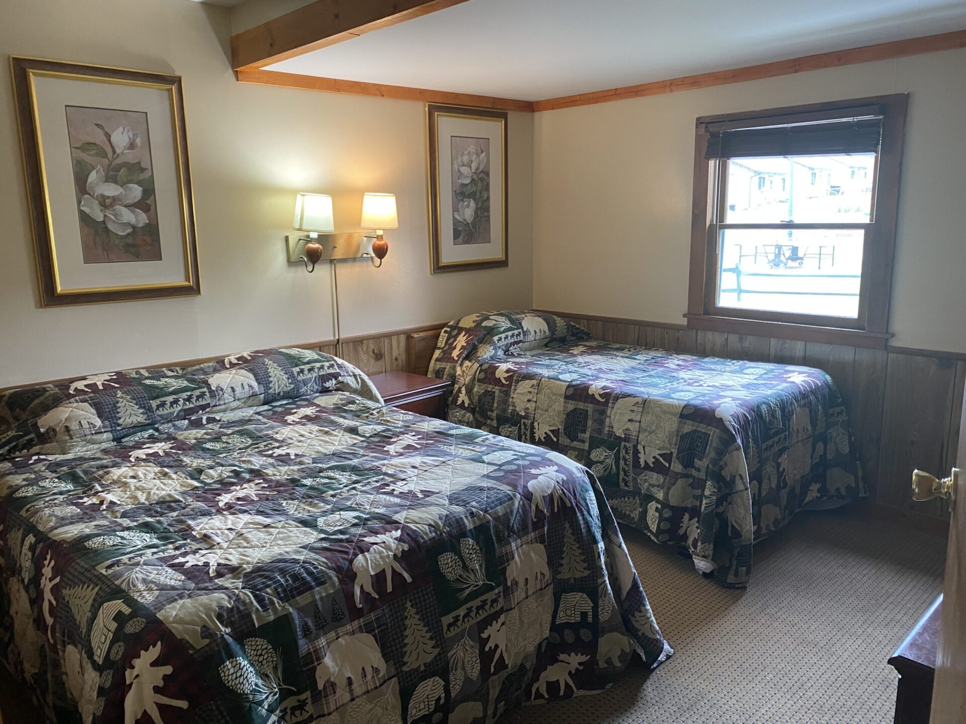 2 beds in bedroom with Adirondack themed blankets